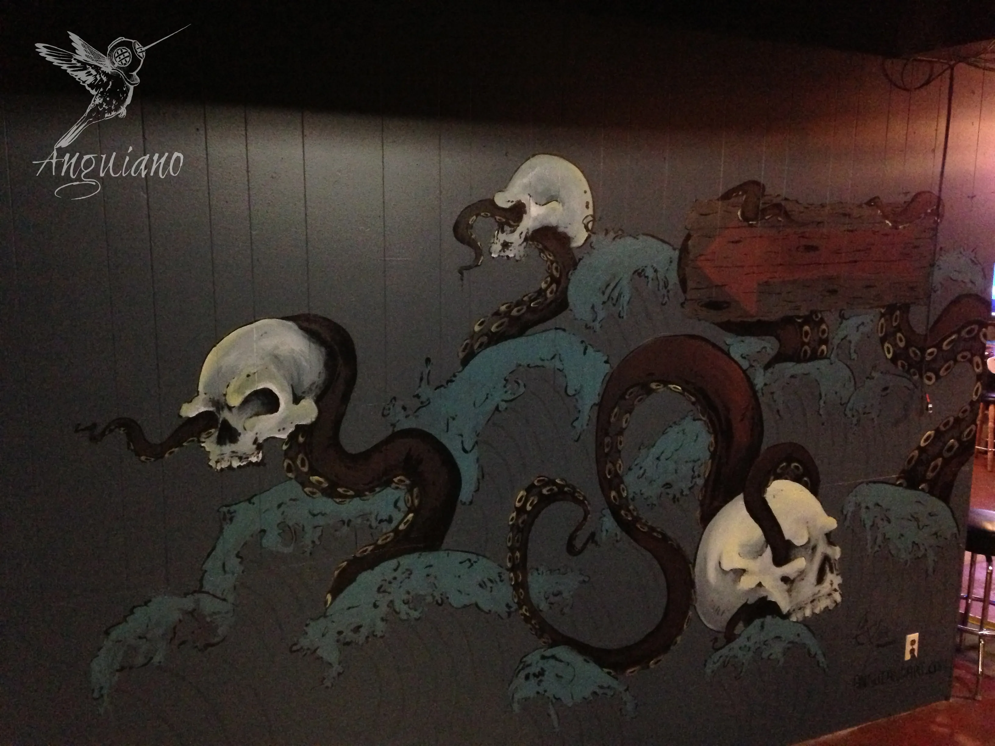 Wall mural painting of skulls entwined with octopus tentacles rising from painted waves